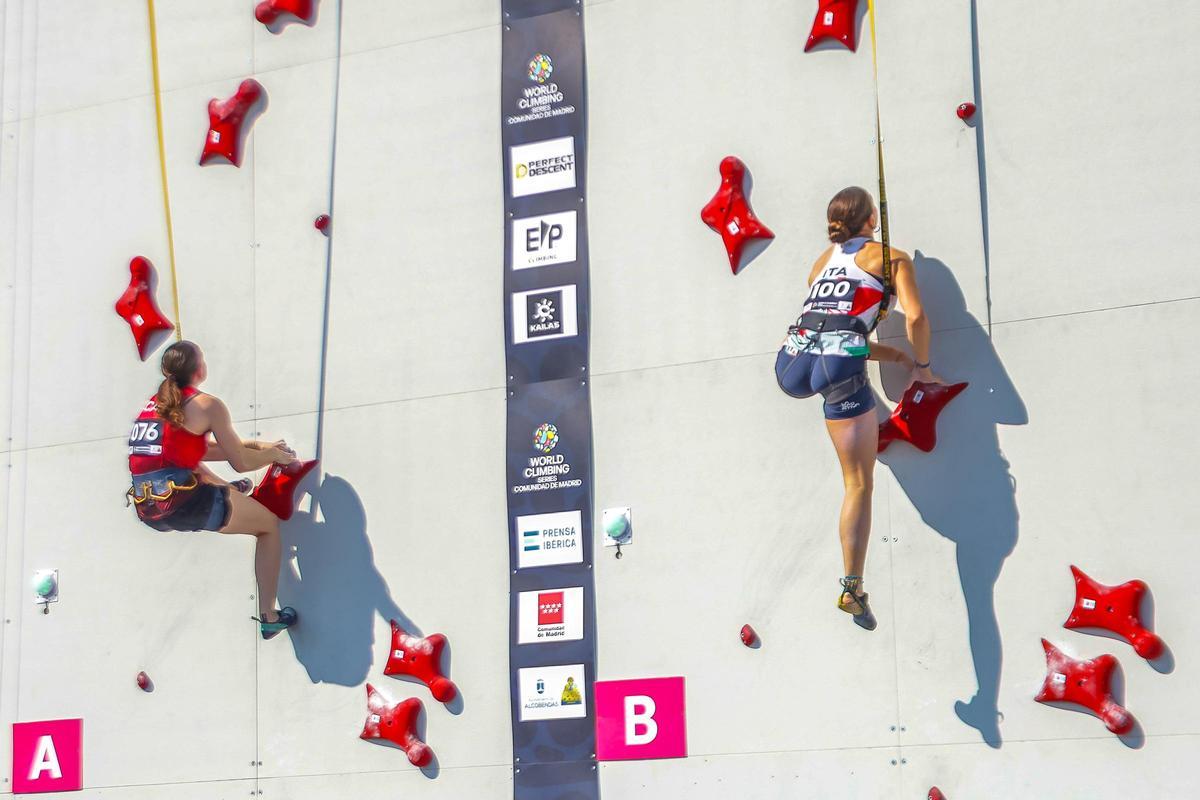 Dos atletas compiten en escalada de velocidad.