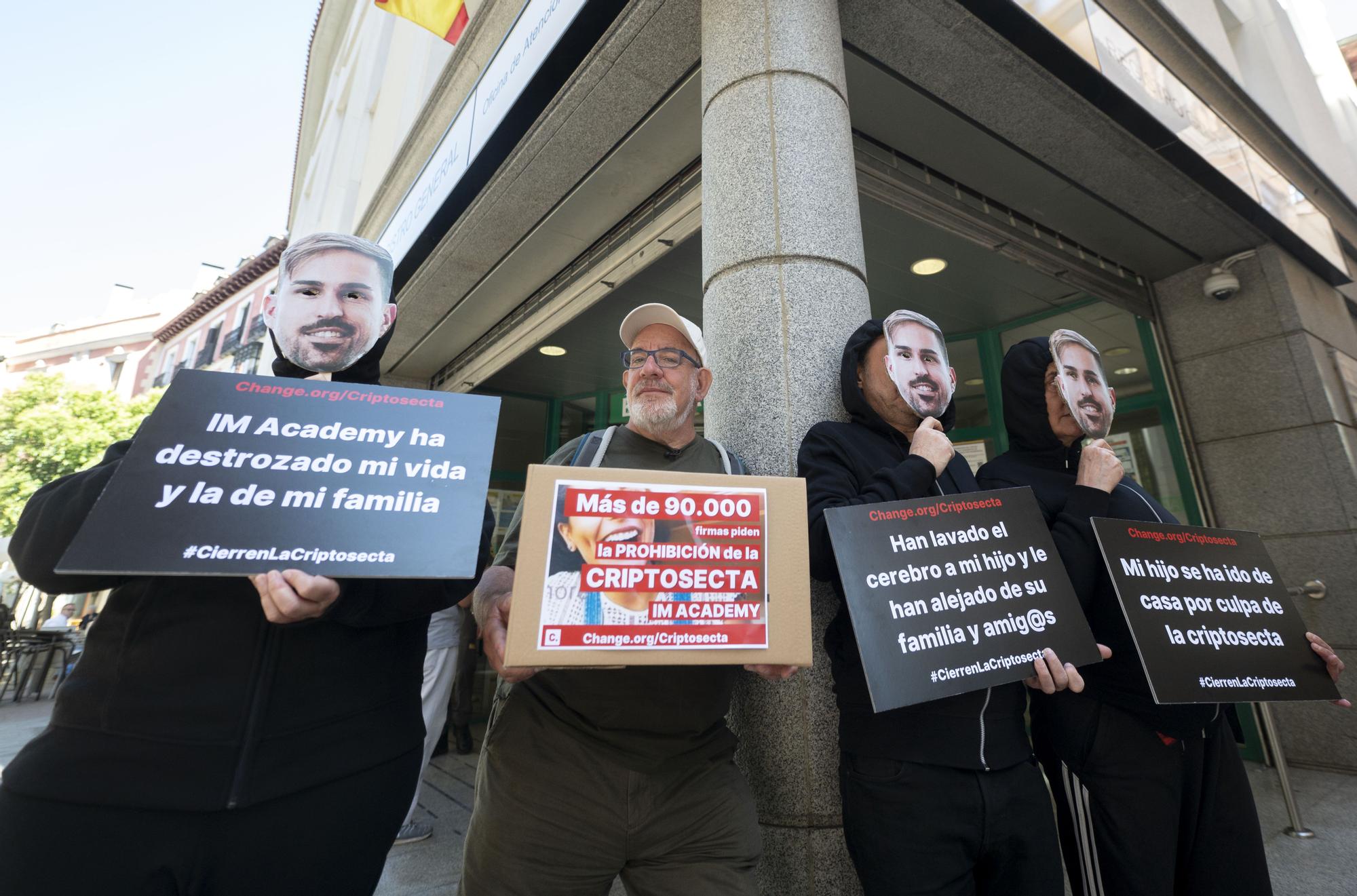 El presidente de la Red de Prevención del Sectarismo y del Abuso de Debilidad (RedUNE), Juantxo Domínguez, acompañado de padres y madres de las víctimas con una máscara del rostro de uno de los líderes de la 'secta', durante una concentración de afectados por la 'criptosecta' IM Academy