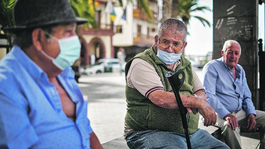 Tres vecinos de San Sebastián de La Gomera conversan en la plaza de Las Américas.