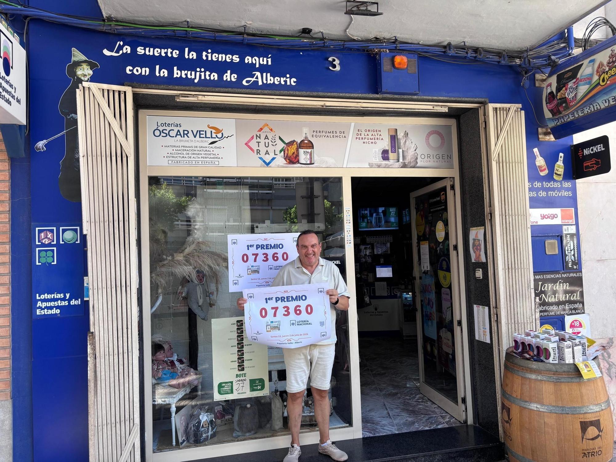 Óscar Vello, a la puerta del establecimiento, con el cartel del número al que ha correspondido el primer premio.