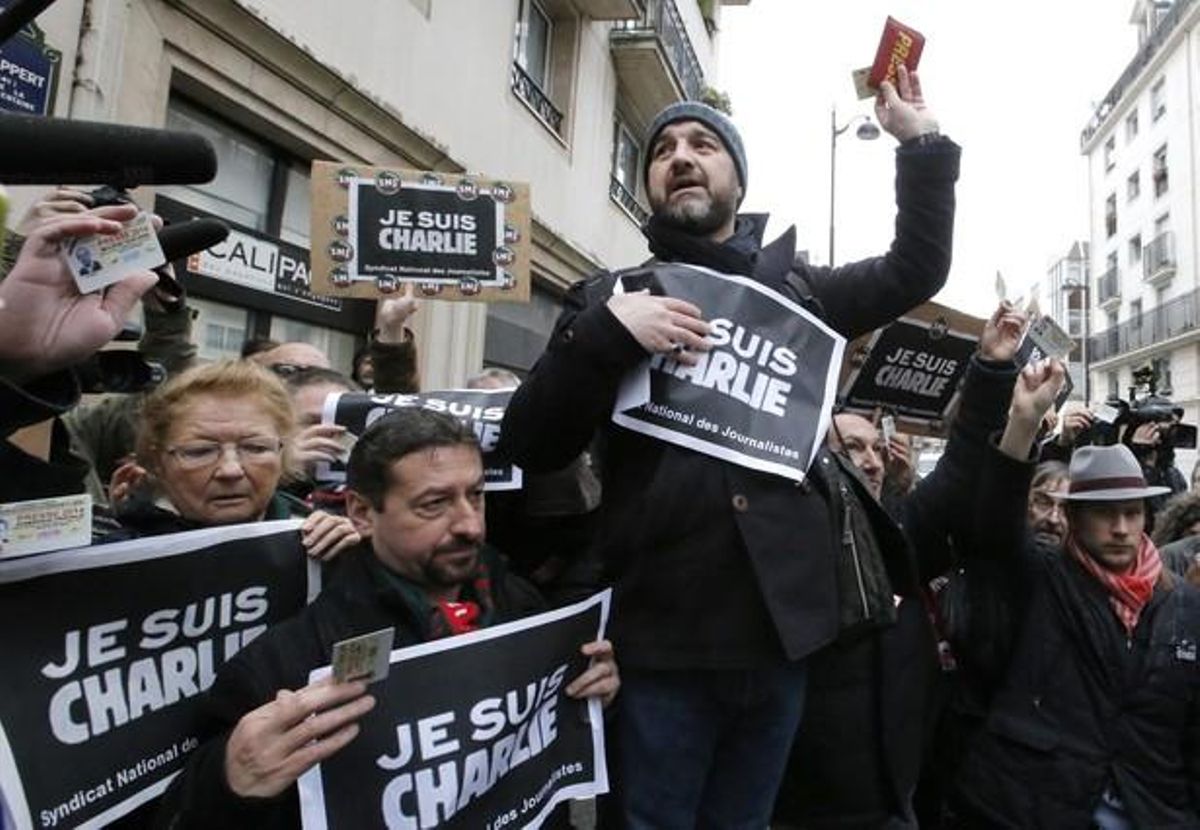 Un periodista ensenya el seu carnet de premsa davant la redacció de la revista ’Charlie Hedbo’.