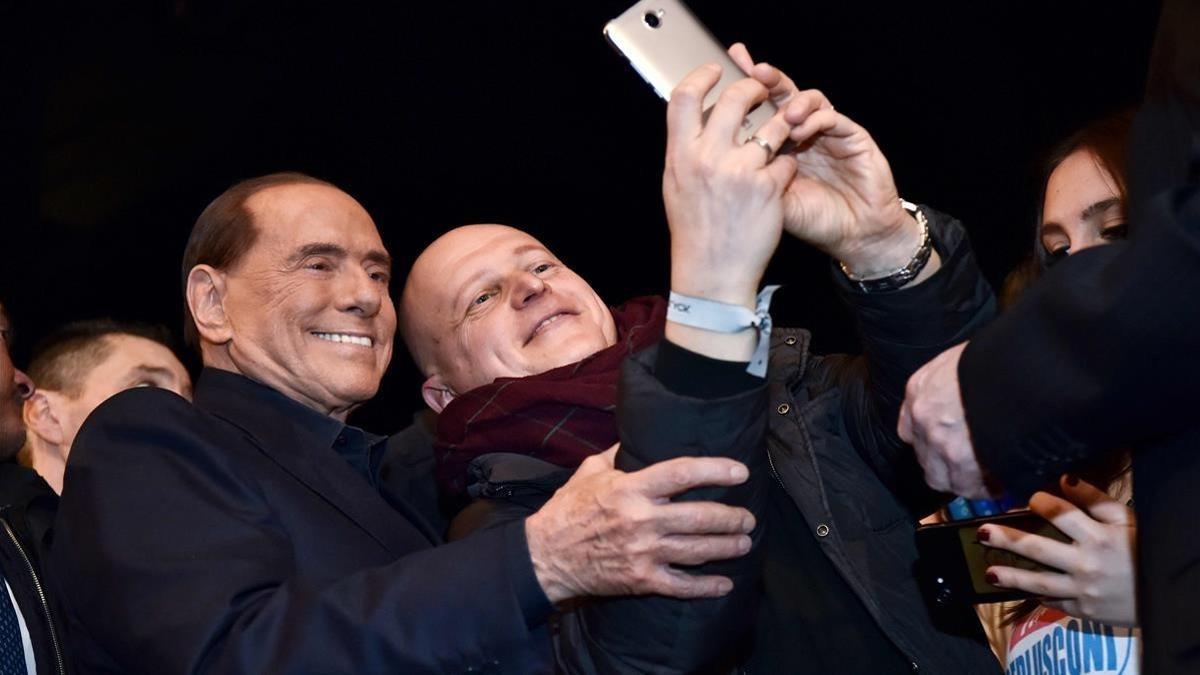 Berlusconi (izquierda) posa para un selfi con un seguidor de Forza Italia, en Milán, el 25 de febrero.