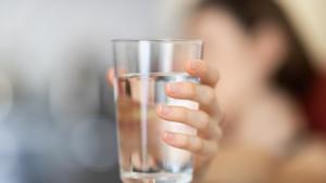 Una persona sostiene un vaso de agua. 