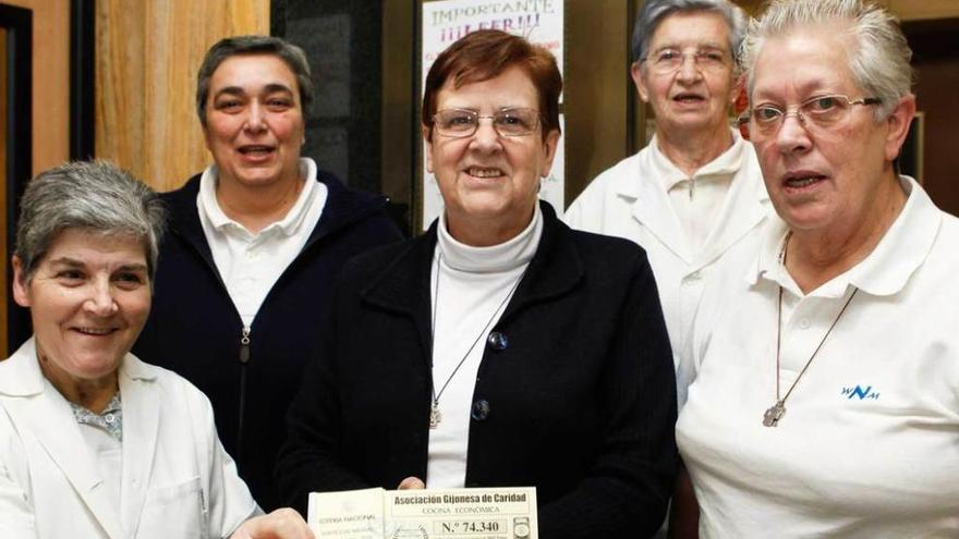 Marisela Cueto, en el centro, con personal de la Cocina Económica mostrando el talonario de la lotería.