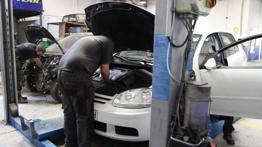 Trabajadores de un taller inspeccionan y reparan varios vehículos.