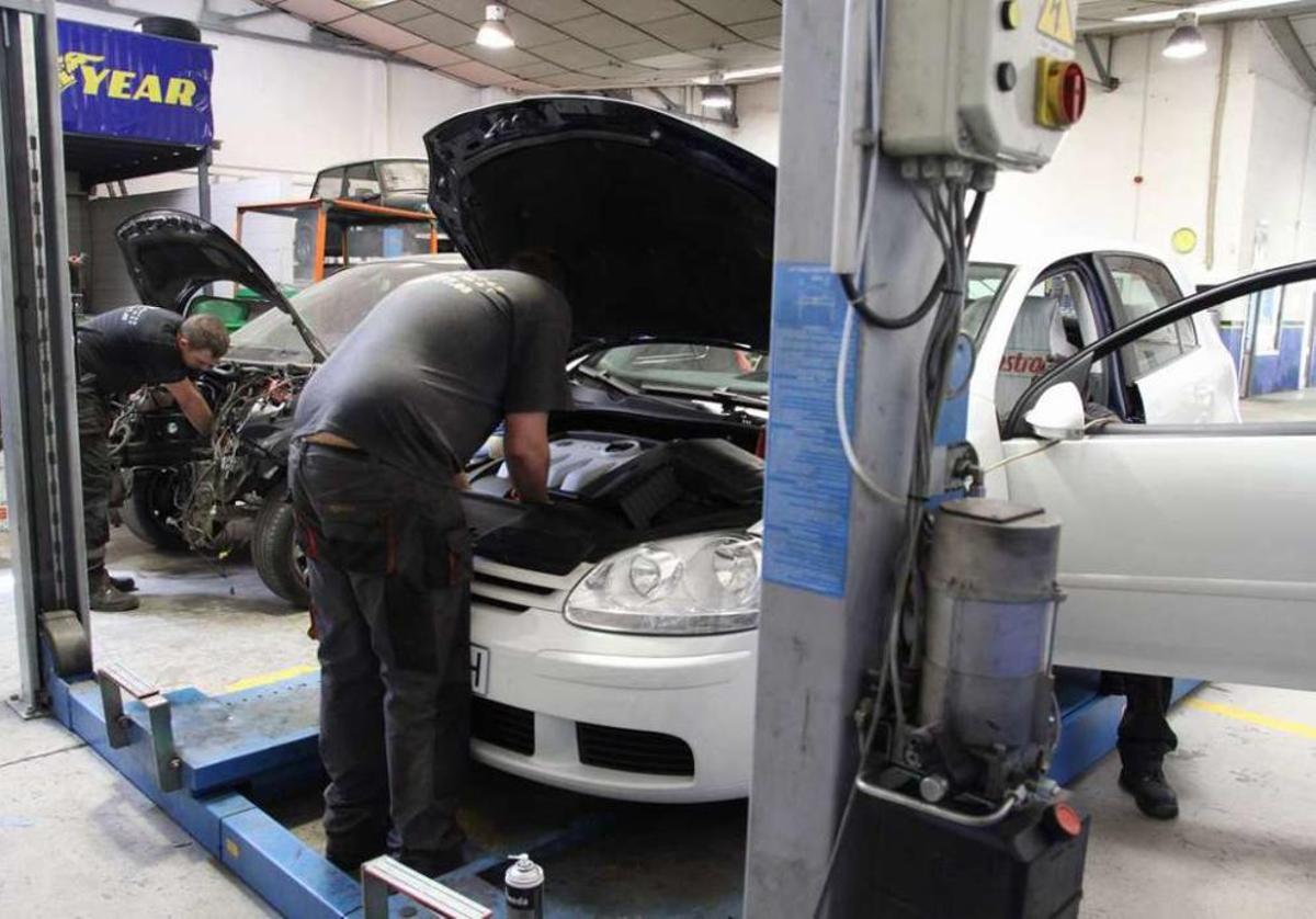 Trabajadores de un taller inspeccionan y reparan varios vehículos. // FDV