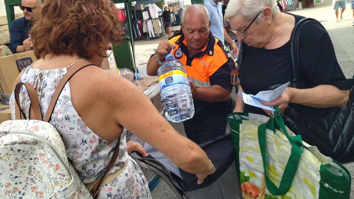 Un voluntario de Protección Civil ayuda a unas vecinas a cargar las garrafas