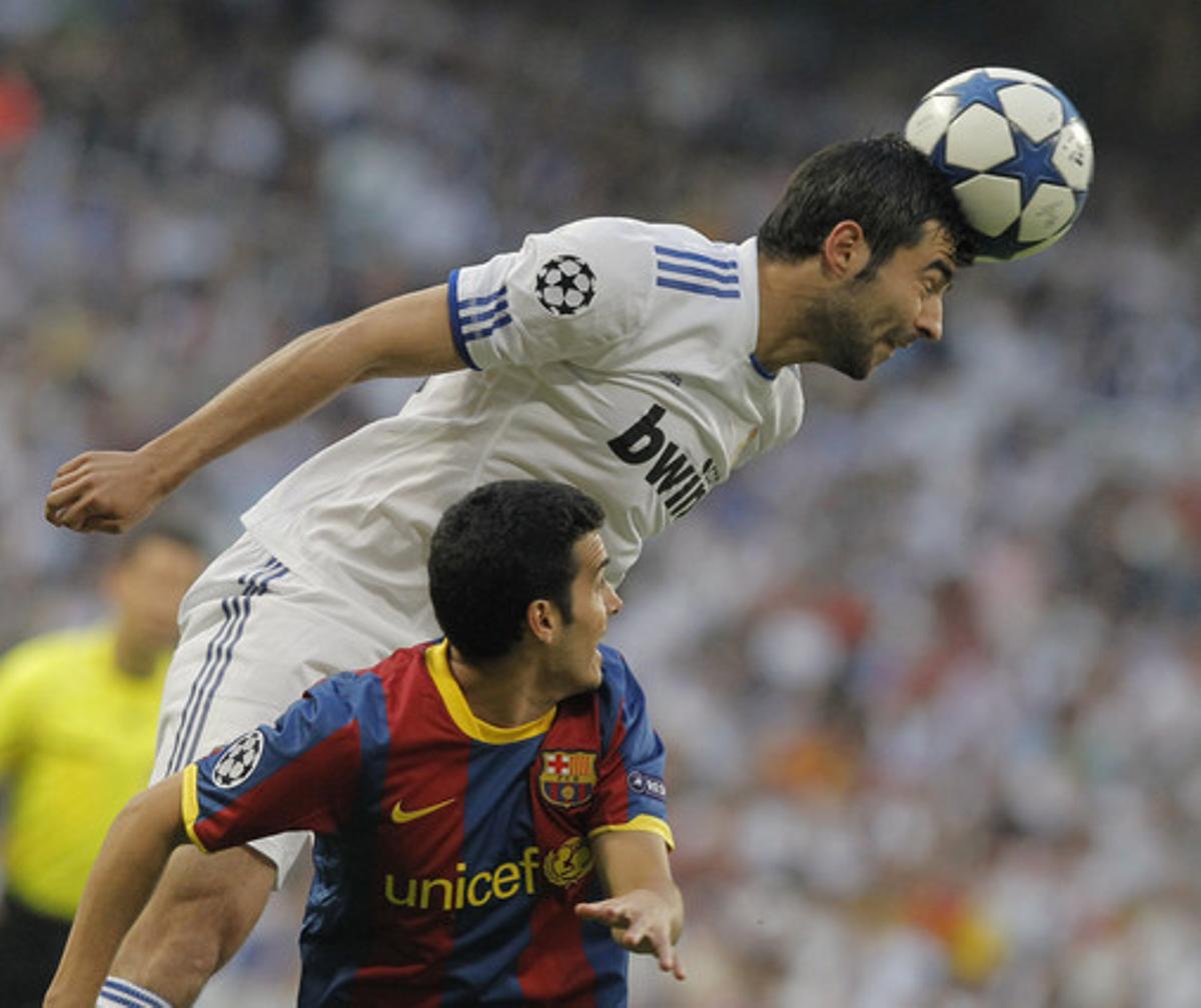 El defensa del Reial Madrid Raúl Albiol toca de cap la pilota davant el davanter del FC Barcelona Pedro Rodríguez.