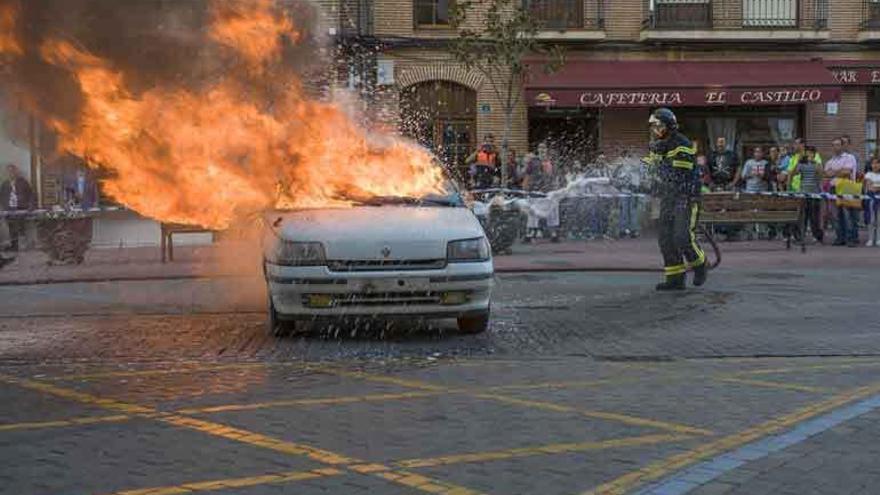 Un bombero sofoca el fuego en un vehículo en un simulacro en la Plaza de la Madera.