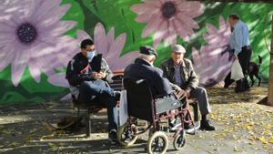 Vecinos del barrio de La Florida toman el sol de invierno en la avenida Primavera, en L’Hospitalet de Llobregat