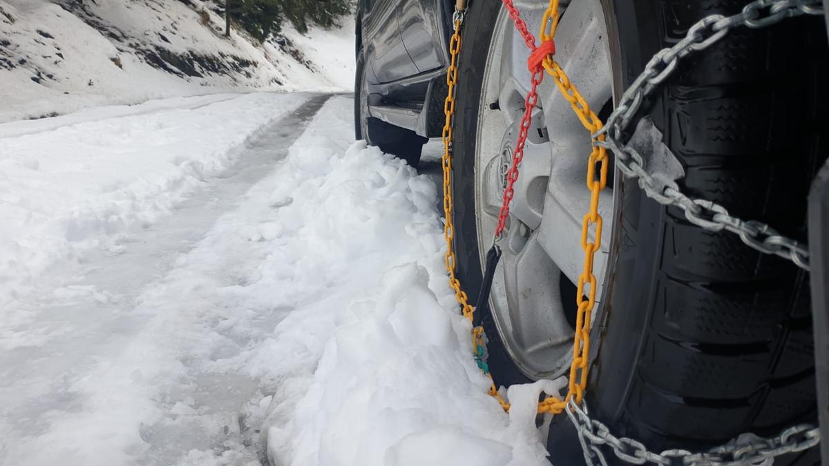 Imagen de un coche con cadenas en una carretera con nieve