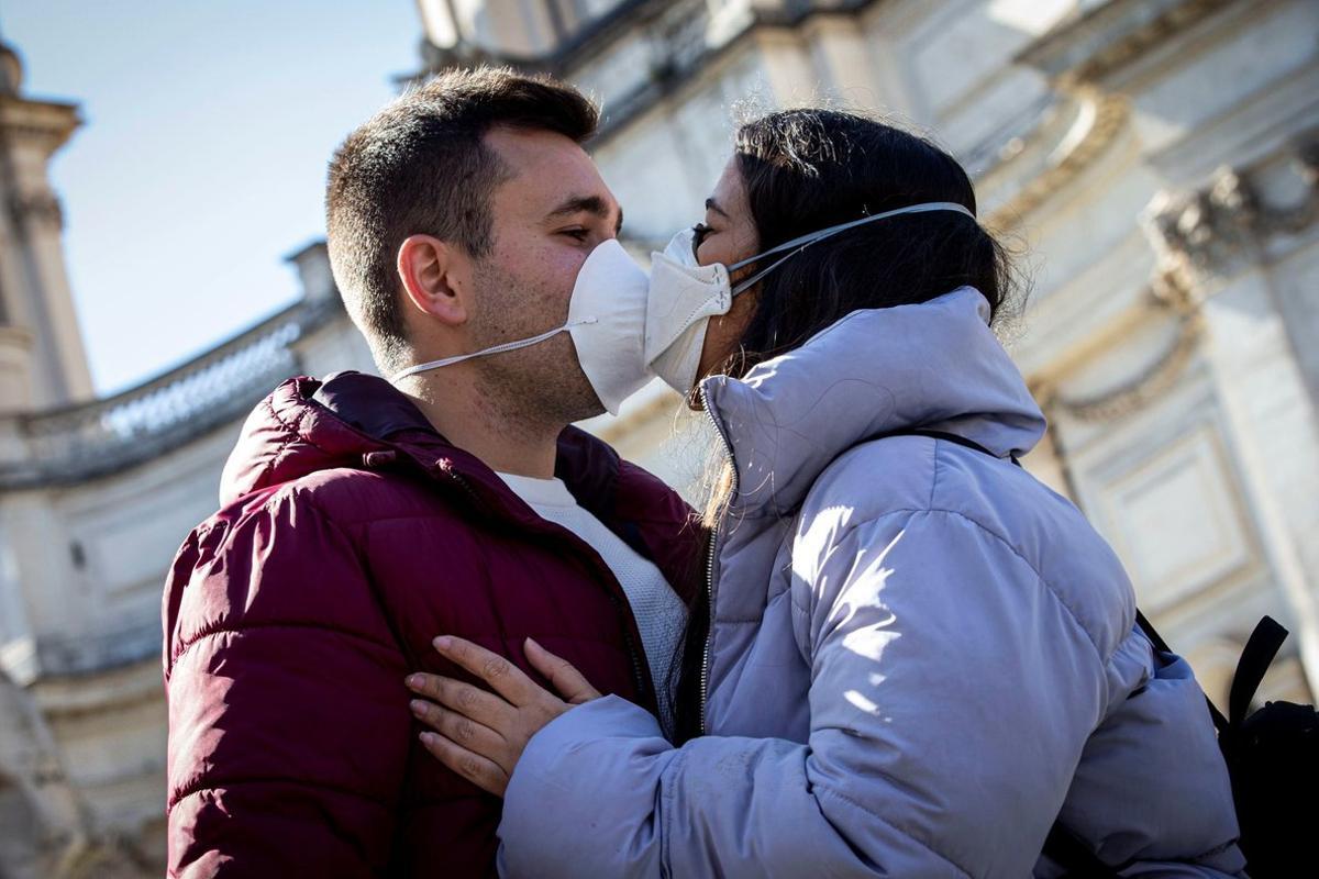 -FOTODELDÍA- EPA044. ROMA (ITALIA), 04/03/2020.- Una pareja se besa con máscaras faciales sanitarias, este miércoles en Roma (Italia), país en el que el coronavirus se sigue expandiendo y ya hay 107 fallecidos de un total de 3.089 contagiados, mientras 276 personas ya se han curado. EFE/ Massimo Percossi