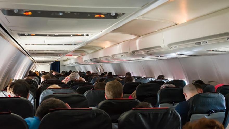 Interior de un avión repleto de pasajeros.