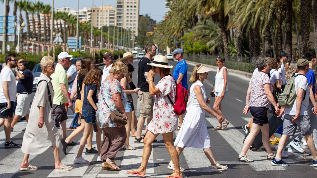 Varios vecinos y turistas pasean por una calle de Alicante