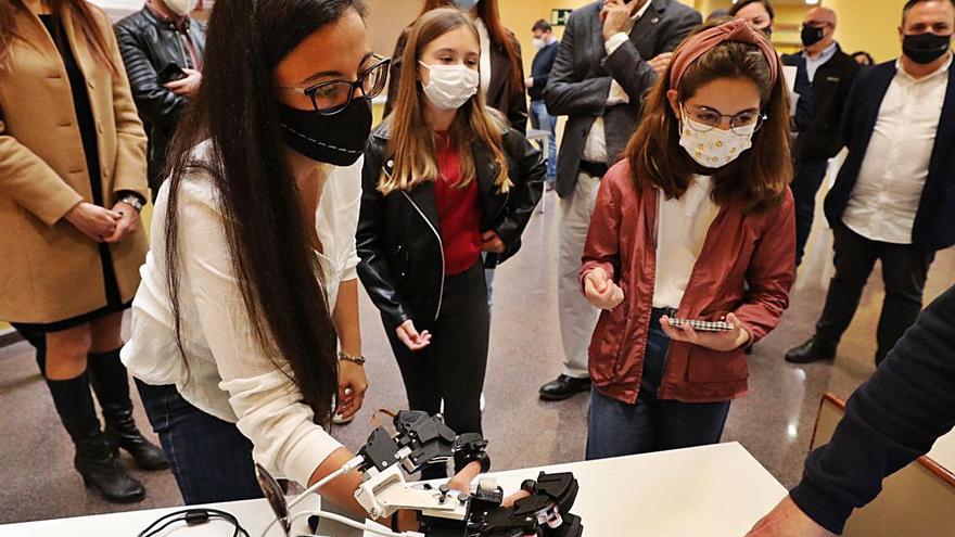 La ingeniera mecánica de la UMH Andrea Blanco expone ayer a las niñas el funcionamiento de un brazo robótico; a la derecha, las menores interactúan con un joystick. | ANTONIO AMORÓS