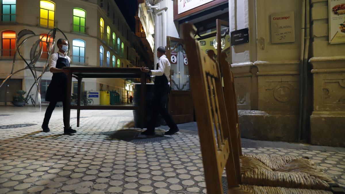 Dos camareros recogen la terraza de un bar en el centro de Málaga.