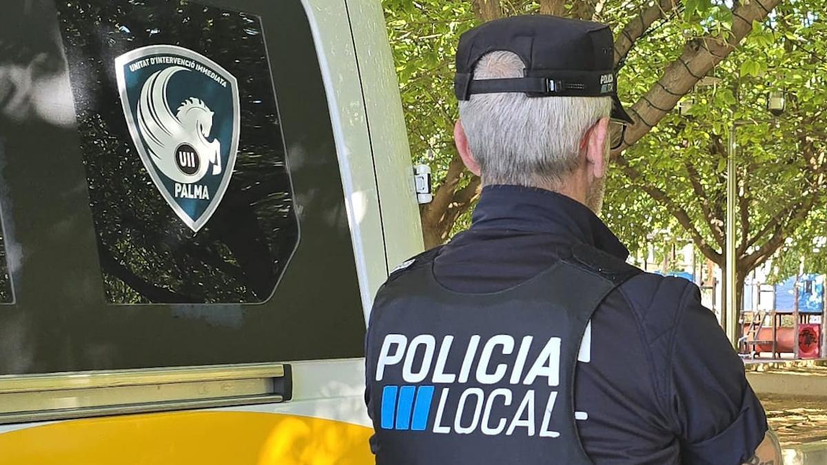 Un agente de la Unidad de Intervención Inmediata (UII) de la Policía Local de Palma, junto a su vehículo.