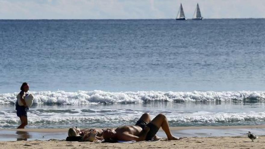 Bañistas tomando el sol en la playa del Postiguet a finales de noviembre