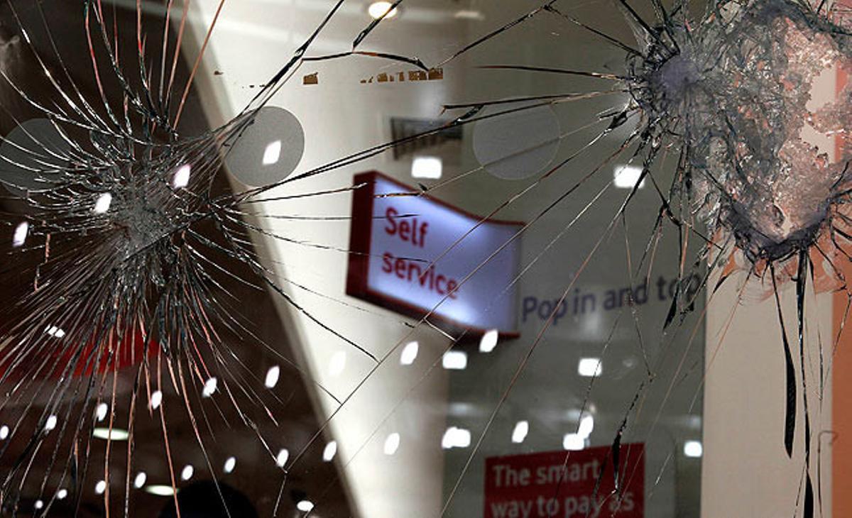 Vidres trencats durant els últims disturbis en una botiga de telefonia mòbil a Manchester.
