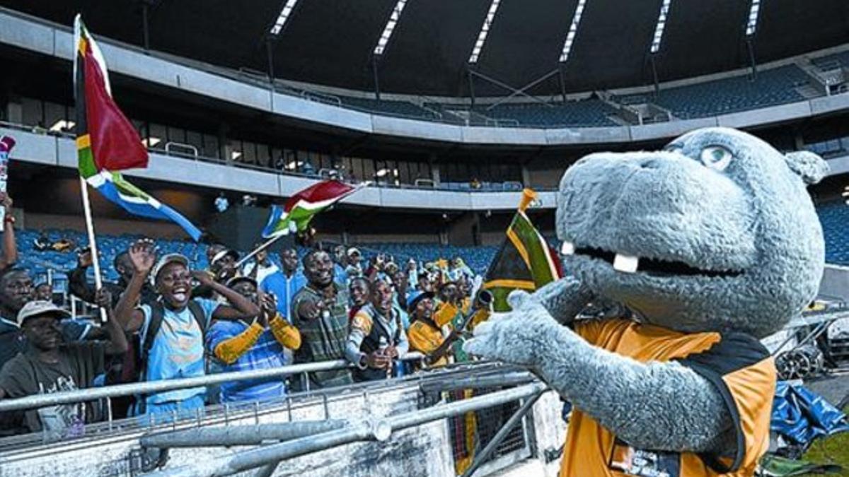 Un seguidor muestra una camiseta de Drogba; la mascota Takuma en Soweto y el astro marfileño, fotografiado por un hincha en Johannesburgo.