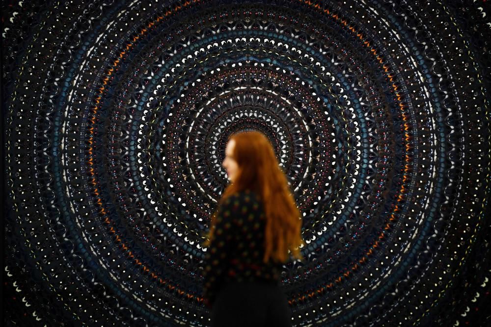Un asistente de la galería posa frente a 'The Creator' de Damien Hirst durante una exposición de su nuevo trabajo titulado 'Mandalas' en el White Cube en Londres.