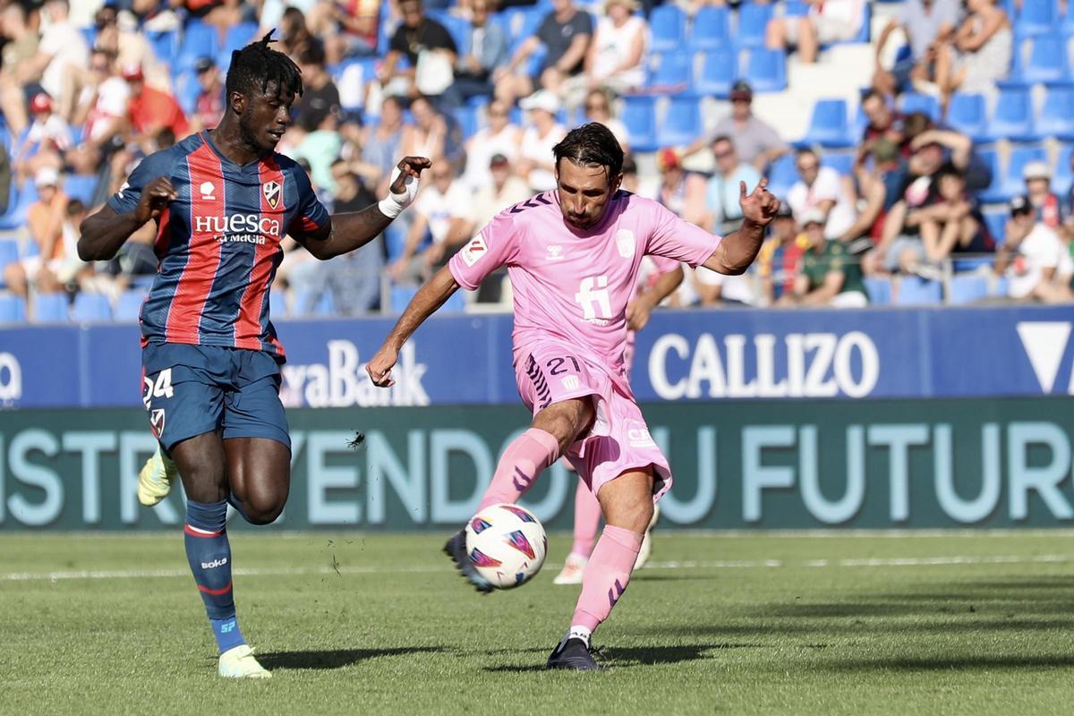 Álex Bernal intenta despejar un balón ante un  jugador del Huesca