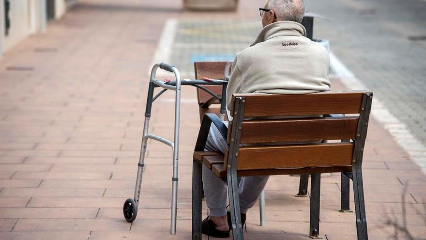 Un hombre de avanzada edad, sentado solo en un banco