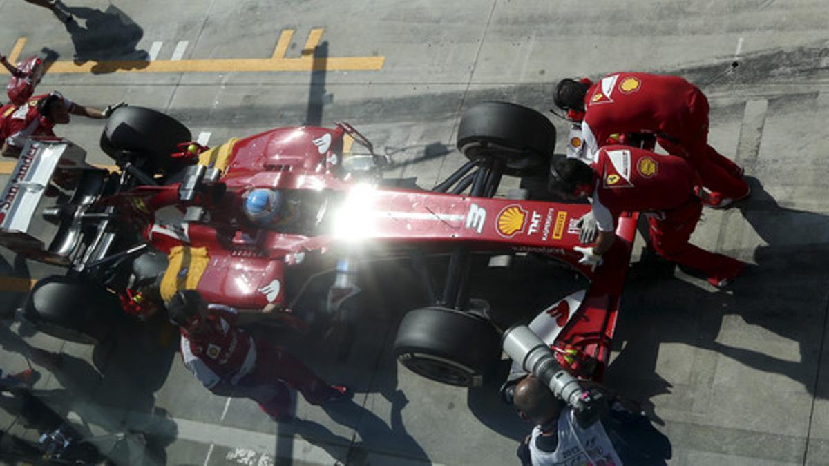 Los mecánicos atienden al coche de Alonso, durante los entrenamientos de ayer en Monza.