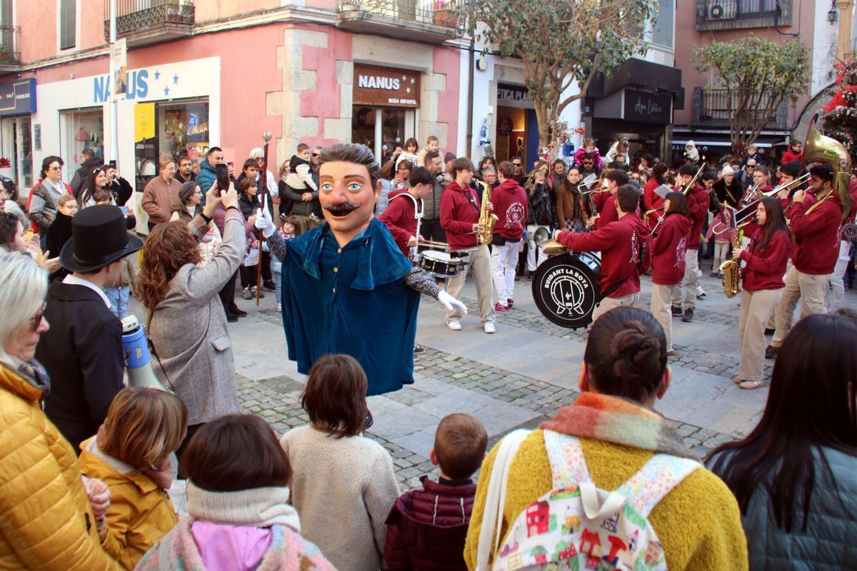 El capgròs de l'Home dels Nassos acompanyat de la xaranga durant la cercavila pel nucli històric de Blanes