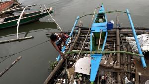 Un pescador amarrando bien su embarcación antes de la llegada del supertifón Doksuri.