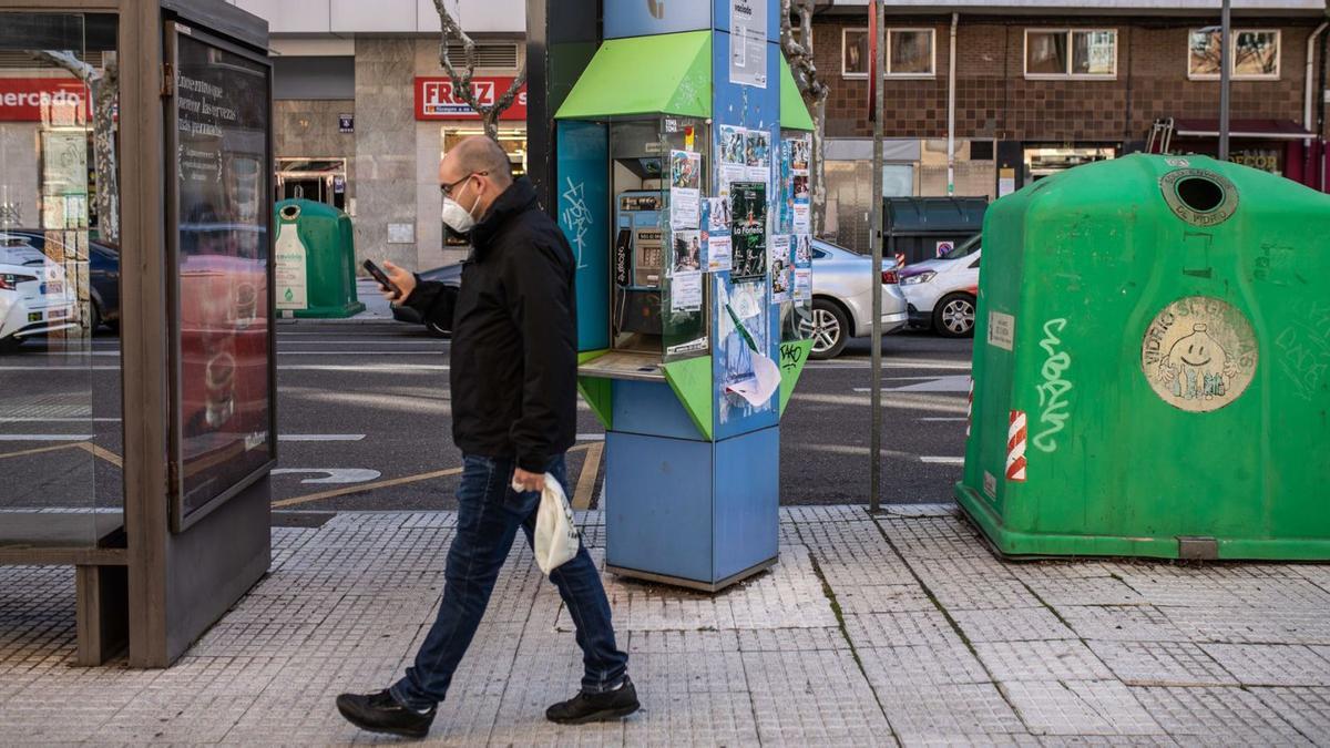 Un homnbre pasa con su teléfono móvil en la mano ante una de las pocas cabinas que quedan en Zamora.