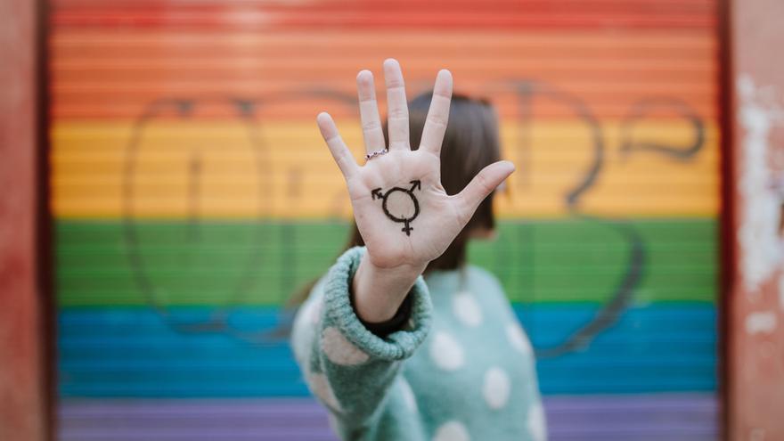 Una mujer frente a la bandera del Orgullo Gay.