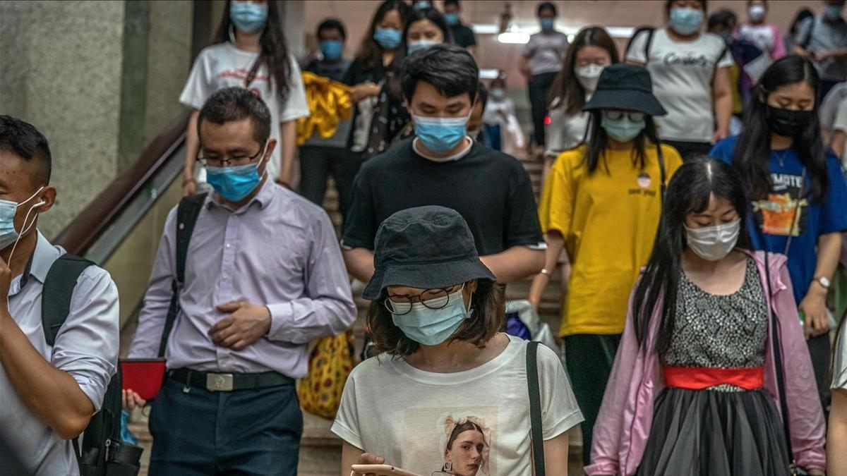 Usuarios del metro de Pekín con mascarillas bajan las escaleras en una estación de la capital china.