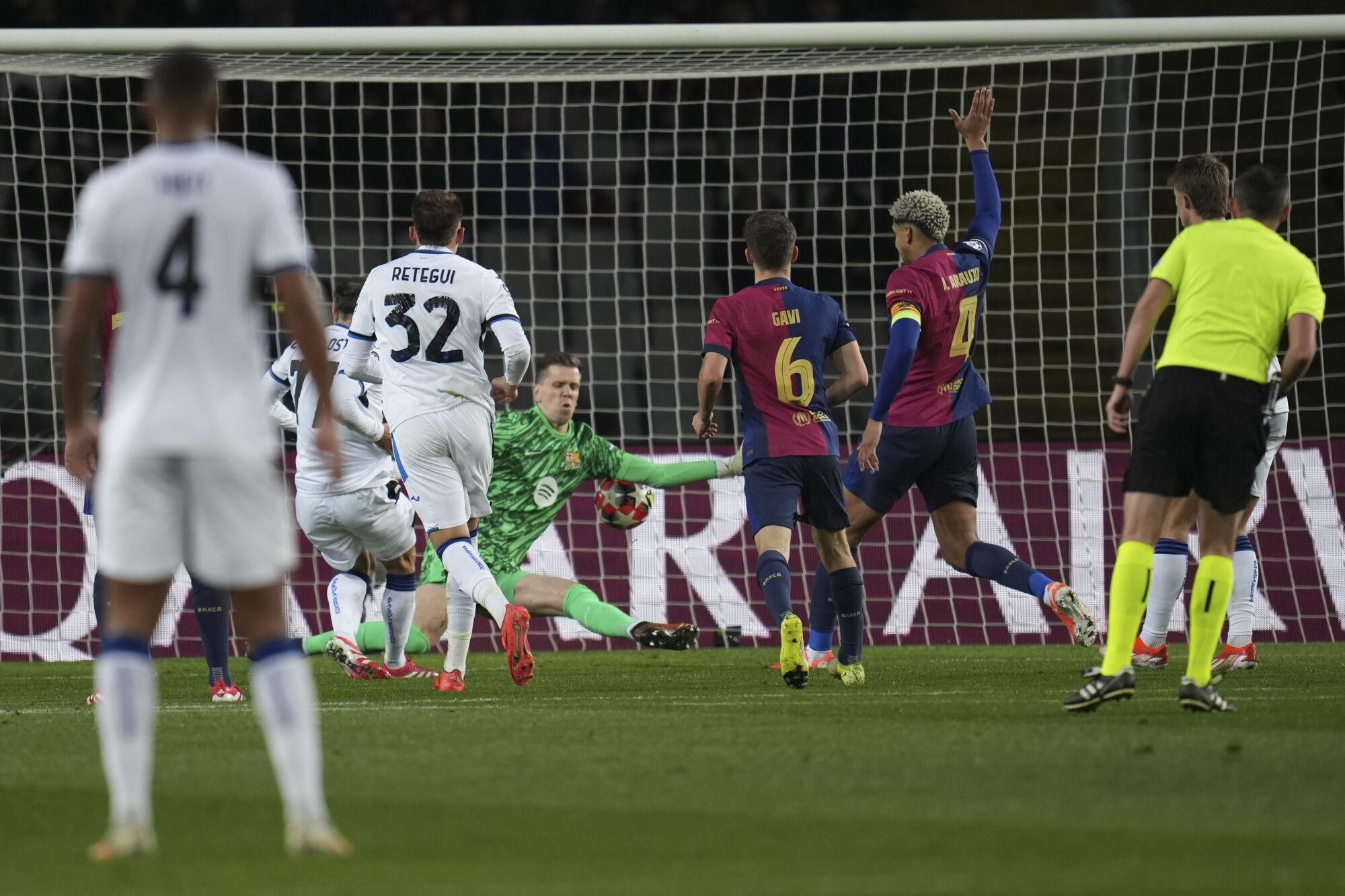 English referee Michael Oliver, right, follows the action as Atalanta's Charles De Ketelaere, left, scores past Barcelona's Wojciech Szczesny, center, a goal that was later disallowed by VAR decision during a Champions League opening phase soccer between Barcelona and Atalanta match at the Lluis Companys Olympic stadium in Barcelona, Spain, Wednesday, Jan. 29, 2025. (AP Photo/Emilio Morenatti)