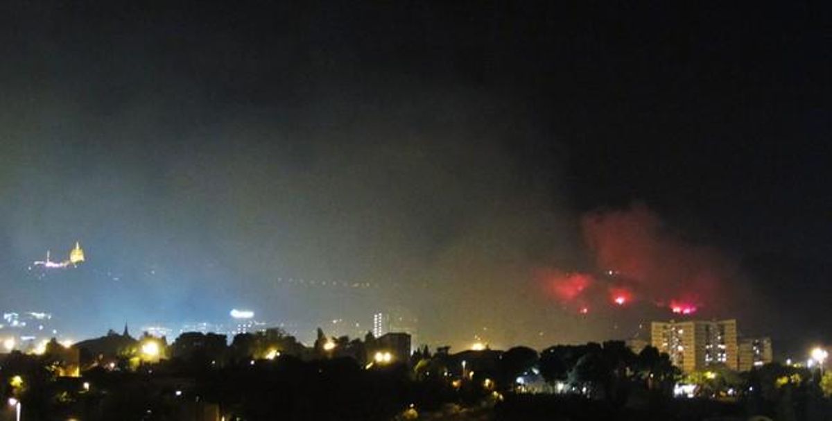 La resplendor de les flames a la zona de la Vall d’Hebron, amb el temple del Sagrat Cor al fons il·luminat.