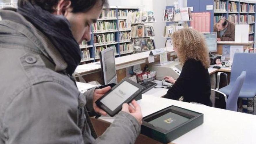 Un joven manipula un «e-book» en la sala de préstamo de adulto.