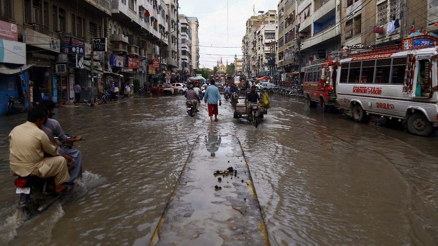 Varios conductores vadean una calle inundada en medio de las inundaciones del monzón en Pakistán.