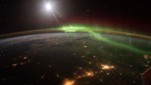 Foto de la Tierra de noche con luces verdes y rojas de una aurora boreal, tomada desde el espacio por el astronauta Scott Kelly, en 2016.