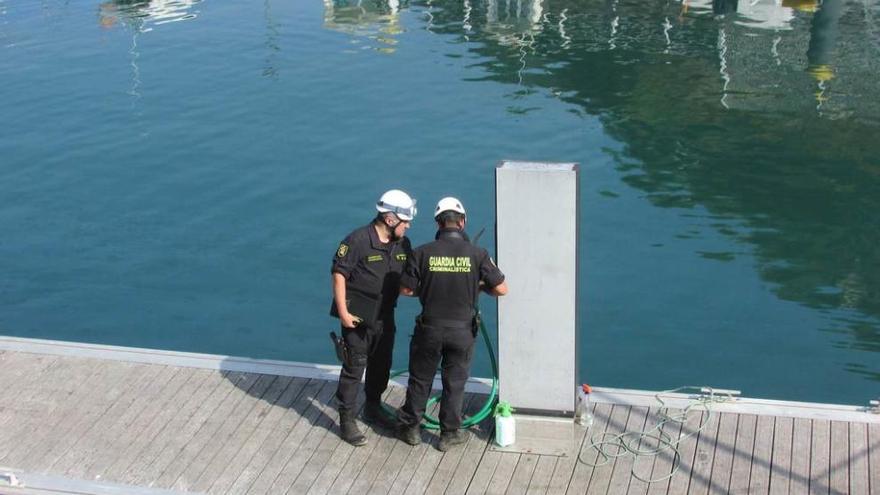 Los agentes de Criminalística, ayer, junto a los surtidores de gasolina del puerto deportivo de Llanes.