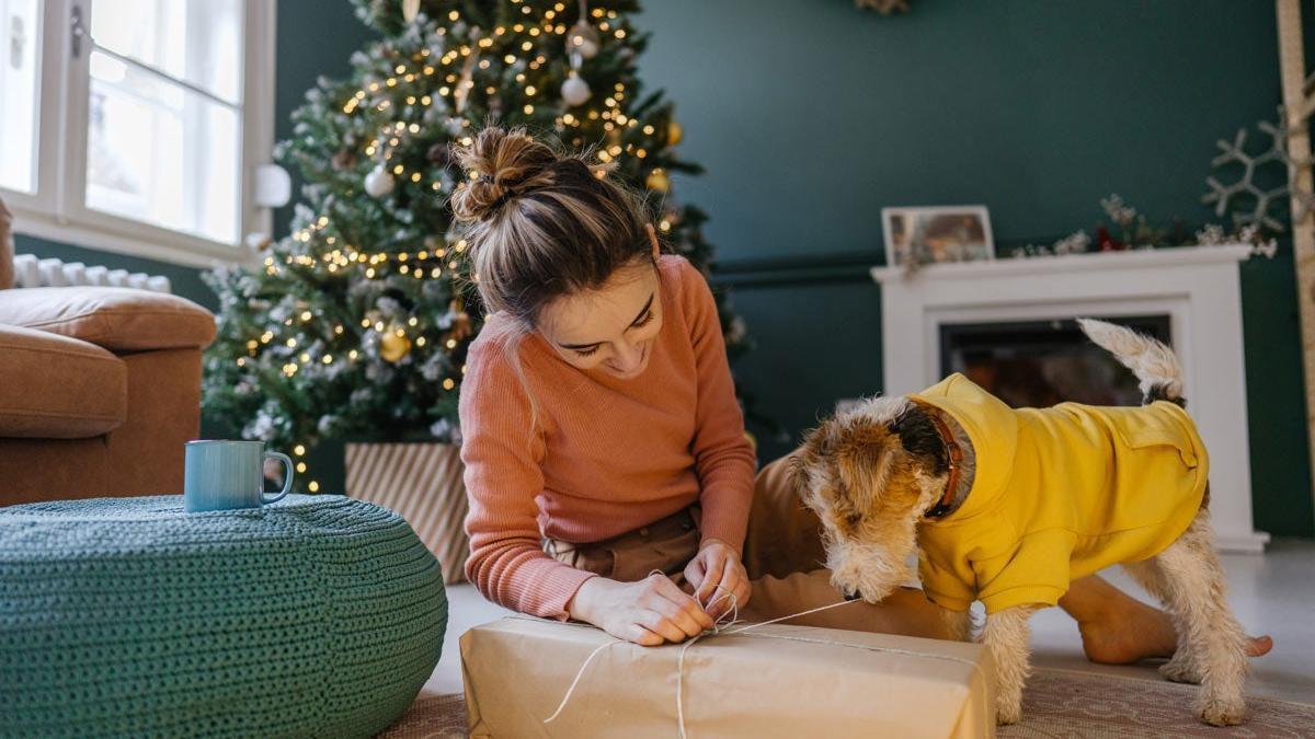 Chica envolviendo regalo de Navidad con perro