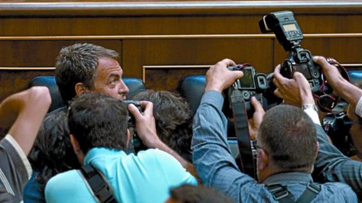 José Luis Rodríguez Zapatero, asediado por los fotógrafos en el momento de ocupar su escaño al inicio de la sesión parlamentaria, ayer por la mañana.