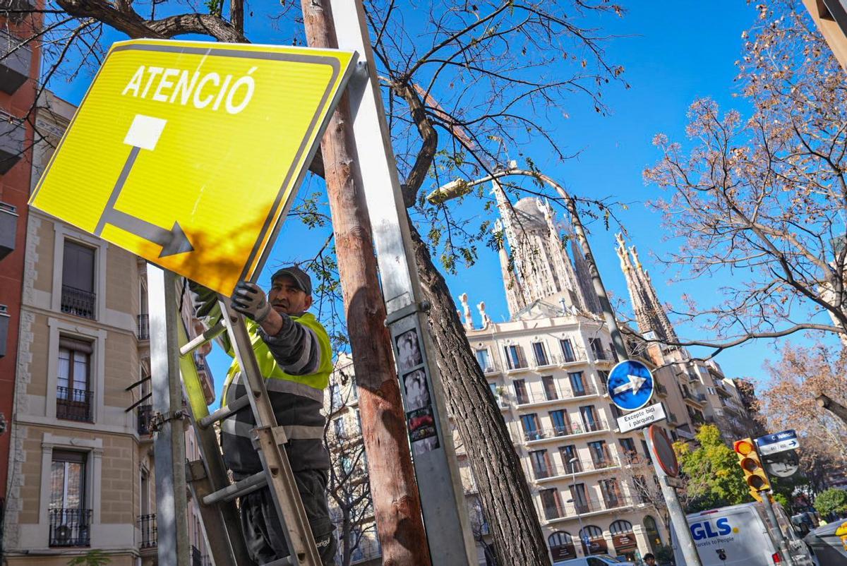 Un operario descuelga por piezas una señal caduca e invisible desde la calzada.