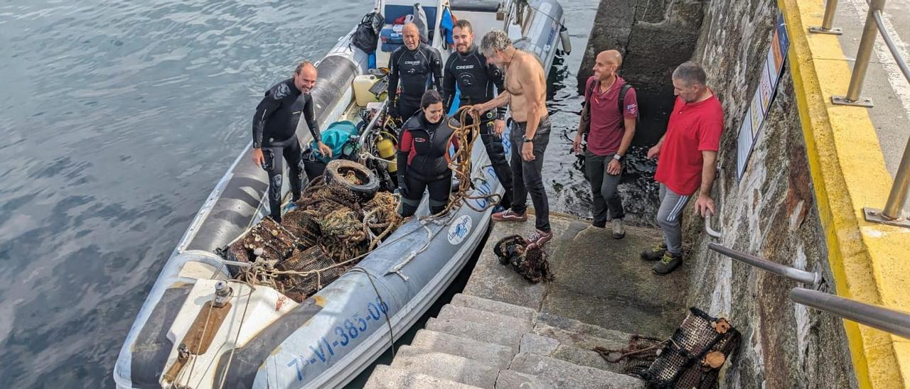Integrantes del Club Buceo Ons y personal del Parque Nacional Illas Atlánticas, en el muelle de Ons con algunos de los residuos retirados del mar.