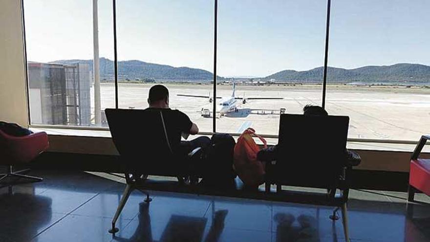 Un viajero espera, sentado, a embarcar en su vuelo. Al fondo, el turbohélice de Air Europa que enlaza diariamente Eivissa con Palma.