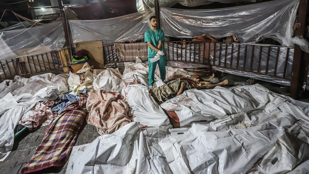 Un sanitario entre los cuerpos de cadáveres en el Hospital Al-Ahli, en Gaza.
