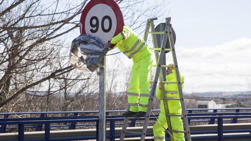 Trabajadores cambian una señal de 100 a 90 kilómetros por hora.