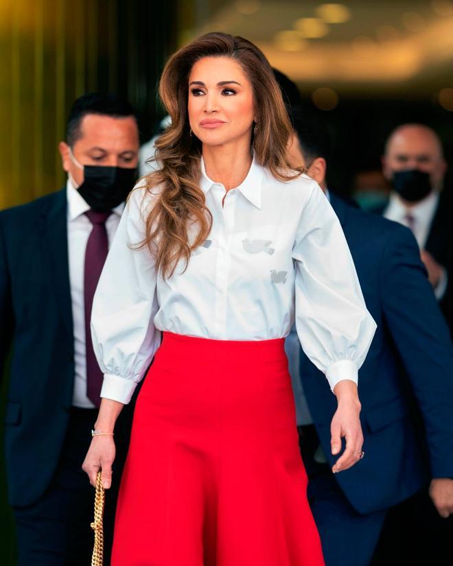 Rania de Jordania con falda roja y camisa blanca con palomas de la paz