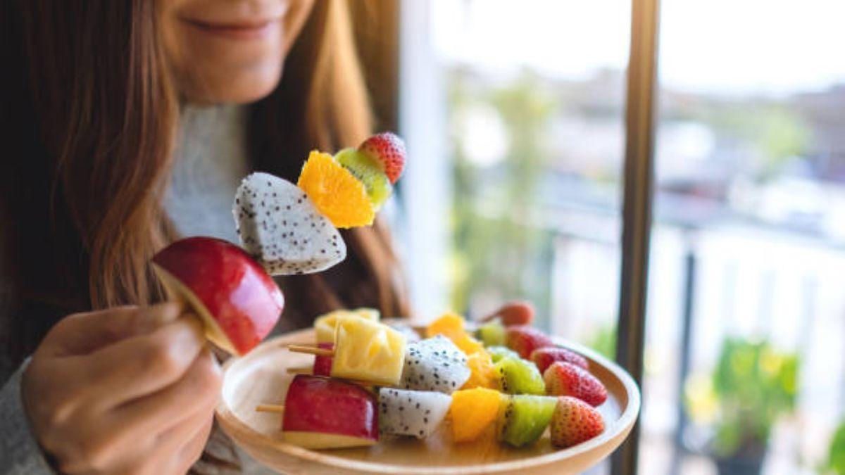 Una persona comiendo una brocheta con frutas