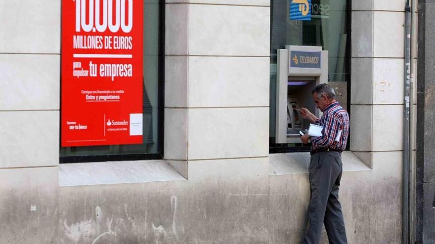 Un hombre saca dinero de un cajero en Málaga.