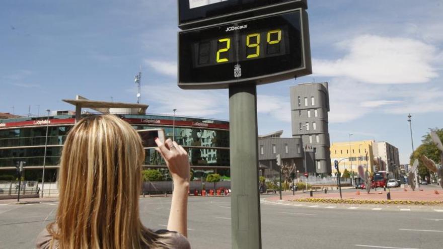 Una joven hace una foto al termómetro de Plaza Castilla, que marca 29 grados.
